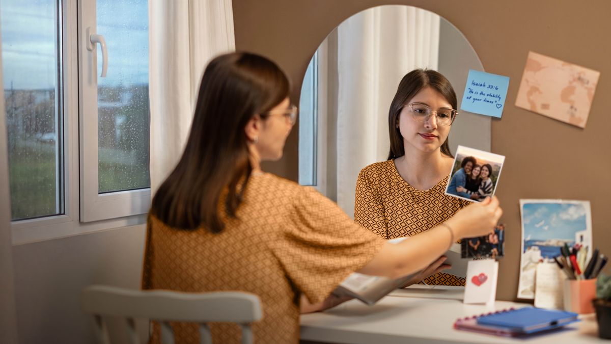 While reading her Bible at her desk, a young sister pauses to look at a photo of her friends.